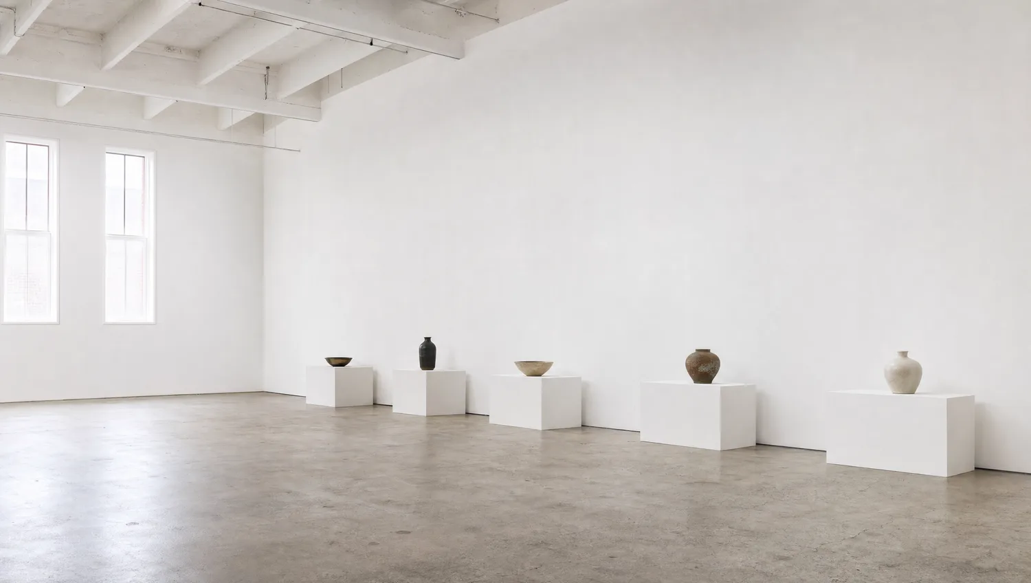 Heller Ausstellungsraum mit einer Reihe niedriger weißer Sockel